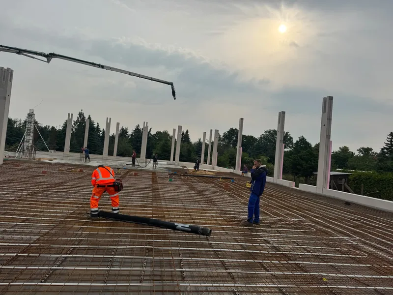 Team mit Betonschlauch auf einer bewehrten Fläche zwischen Betonstützen